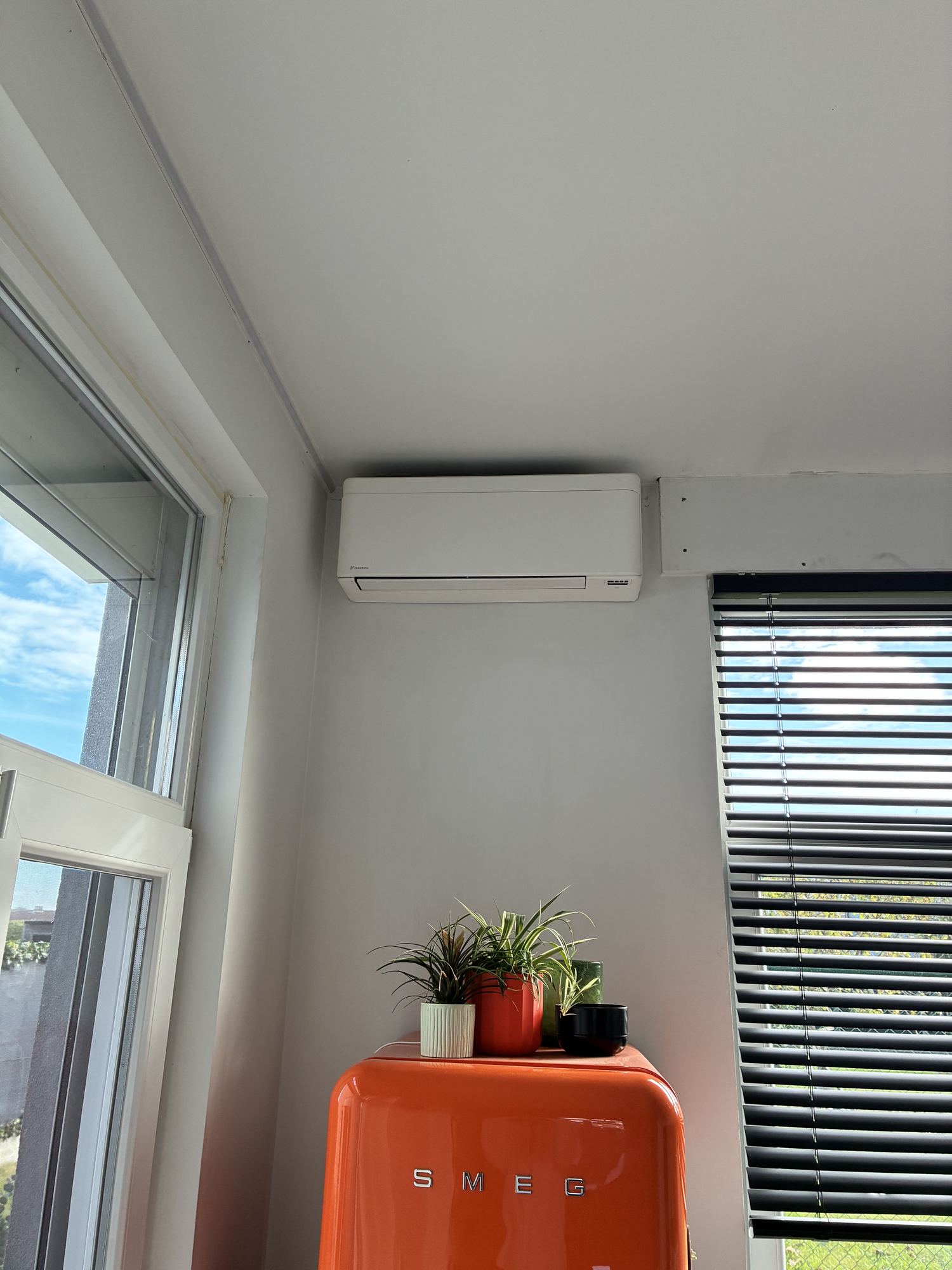 Airco-installatie Melis Cooling, wandunit boven een oranje koelkast